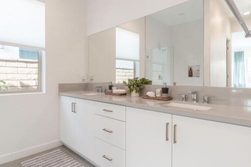 a white bathroom with two sinks and a mirror at Spectacular PGA West New Home! in La Quinta