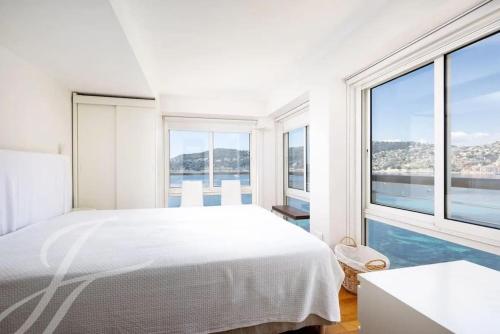 - une chambre blanche avec un grand lit et de grandes fenêtres dans l'établissement Villa Mariella, à Saint-Jean-Cap-Ferrat