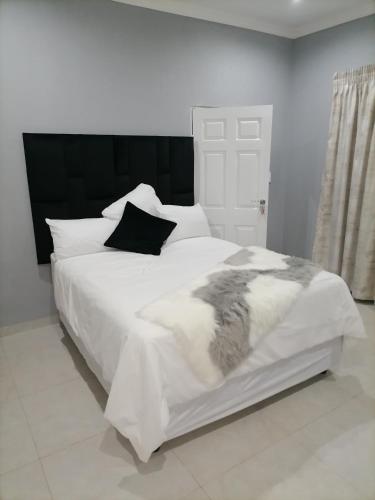 a white bed with black and white sheets and pillows at Serenity Airb&b Protea Glen in Soweto