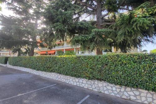 eine Hecke vor einem Gebäude mit Bäumen in der Unterkunft Cagnes/Mer Hippodrome - Terrasse 20m² proche mer in Cagnes-sur-Mer