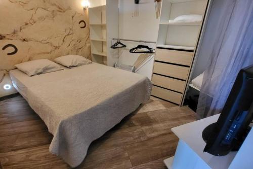 ein kleines Schlafzimmer mit einem Bett und einem TV in der Unterkunft Cagnes/Mer Hippodrome - Terrasse 20m² proche mer in Cagnes-sur-Mer