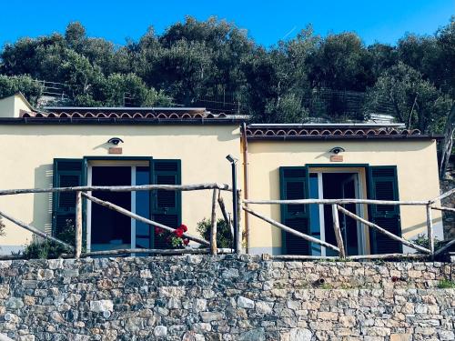 a building with green windows and a stone wall at Eufonia del Mare in Finale Ligure