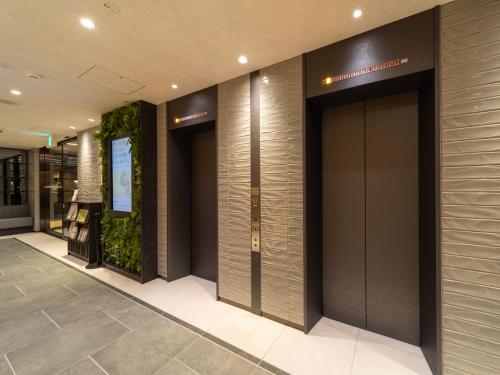 una hall con tre ascensori in un edificio di Super Hotel Premier Sendai Kokubuncho Tennenonsen a Sendai