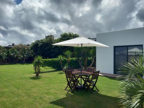 a table and chairs under an umbrella in a yard at Villa - Sleeps 4 & Free Parking in Ribeira Grande