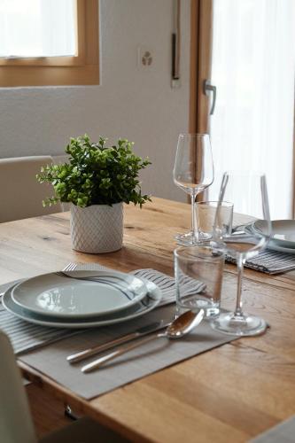 a wooden table with plates and wine glasses on it at Ferienwohnung - 100m von der Talstation Aletsch Bahnen und Bahnhof Fiesch, BESTE Ausgangslage in Fiesch