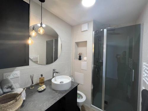 La salle de bains est pourvue d'un lavabo et d'une douche avec un miroir. dans l'établissement Appartement 2 pièces Antibes Mer - Piscine, Parking, Tennis, Wifi…, à Antibes