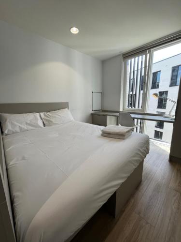 a white bed in a room with a large window at Eyre Square Galway Central Self Catering in Galway