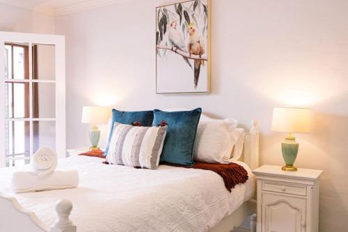 Dormitorio blanco con cama con almohadas azules en Laundry Lane Cottage, en Stroud