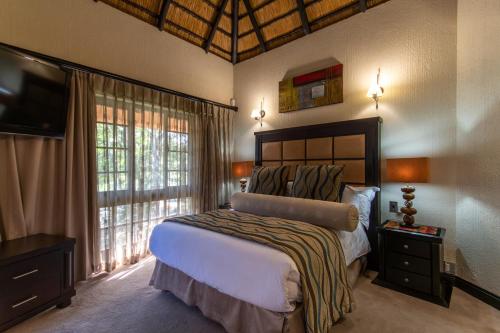a bedroom with a bed and a large window at Kruger Park Lodge Unit No. 209 in Hazyview