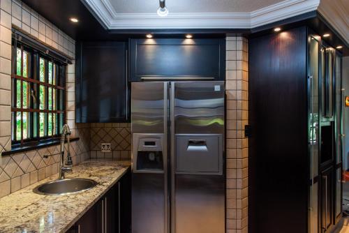 uma cozinha com um frigorífico de aço inoxidável e um lavatório em Kruger Park Lodge Unit No. 209 em Hazyview