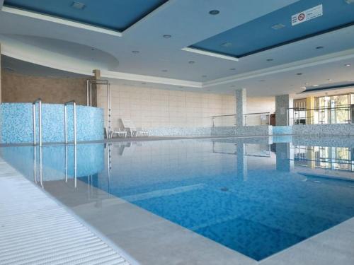 a large swimming pool with blue water in a building at ‘Good Feelings’ in Siófok