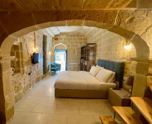 a bedroom with a bed in a stone wall at Ta Pinu Guesthouse in Għarb