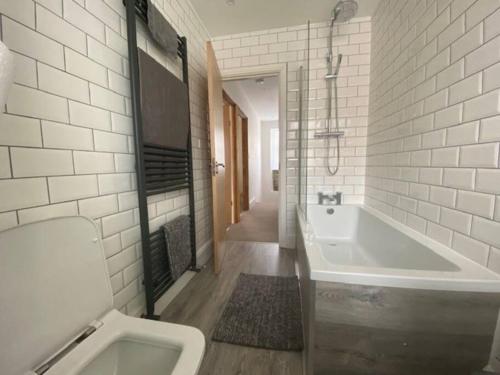 a bathroom with a tub and a toilet and a sink at Ivybridge Cottage in Ivybridge