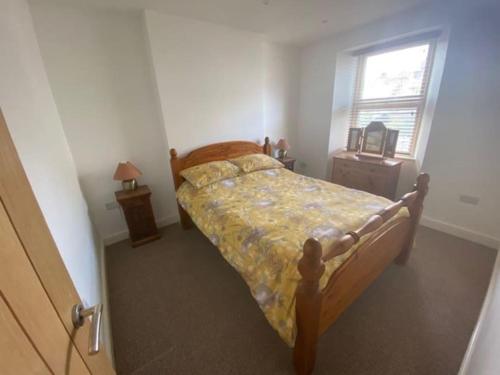 1 dormitorio con 1 cama con colcha amarilla y ventana en Ivybridge Cottage, en Ivybridge