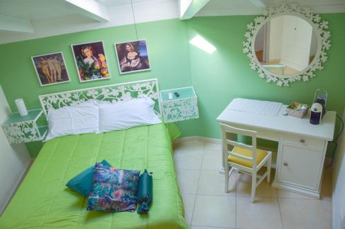グラヴィーナ・イン・プーリアにあるB&B Santa Sofiaの緑のベッド、デスク、鏡が備わるベッドルーム1室が備わります。
