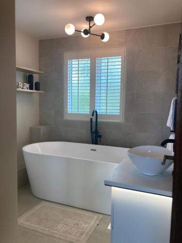 a bathroom with a large white tub and a sink at Greensfield Close 