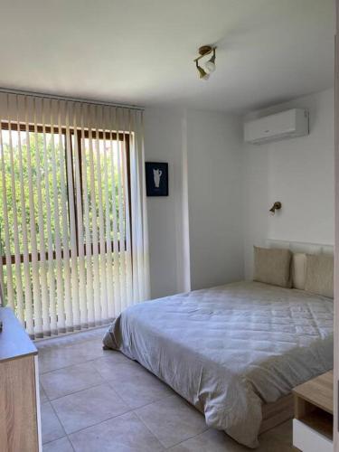 a bedroom with a large bed and a large window at Brand new, luxury beach flat in Tsarevo