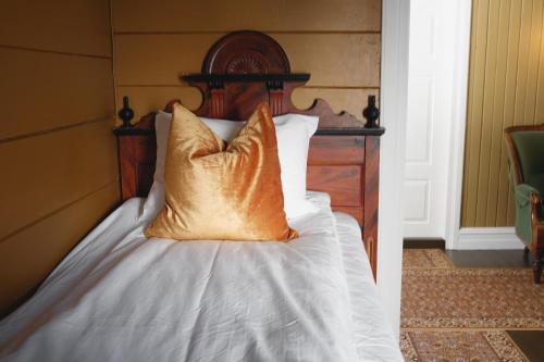 a bed with a wooden headboard with a pillow on it at Sylte Hotell, Valldal in Valldal