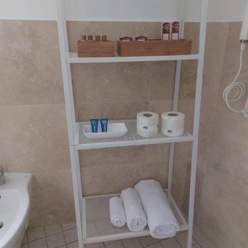 a bathroom with a shelf with towels and a sink at AURUM Affittacamere in Loreto