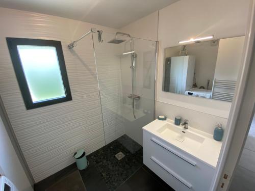 a white bathroom with a sink and a shower at 2 Maisons de vacances Sittelles Lodge in Concarneau