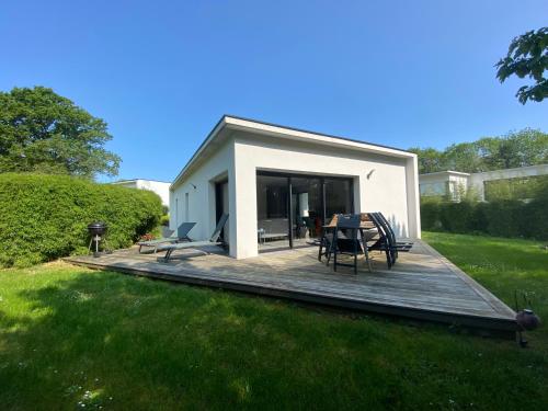 a house with a wooden deck in a yard at 2 Maisons de vacances Sittelles Lodge in Concarneau