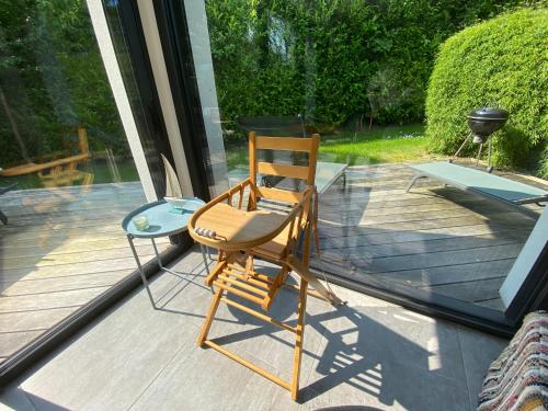 a wooden chair sitting on top of a deck at 2 Maisons de vacances Sittelles Lodge in Concarneau