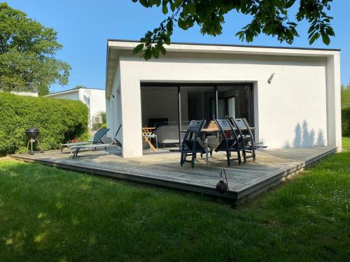a wooden deck with chairs and a table in a yard at 2 Maisons de vacances Sittelles Lodge in Concarneau