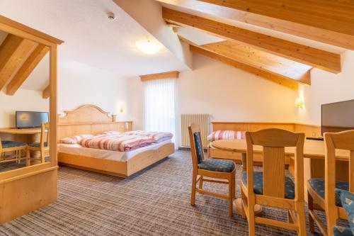 a bedroom with a bed and a table and chairs at Albergo Canazei in Canazei