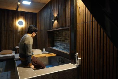 a man sitting in a room with a fireplace at Spring Night in Jeonju