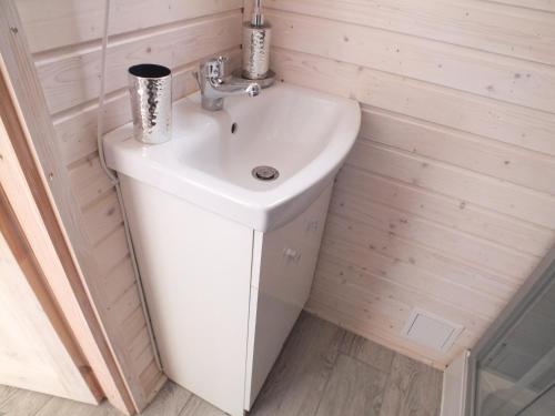 La salle de bains est pourvue d'un lavabo blanc. dans l'établissement Domki letniskowe- Magnoliowa przystań, à Firlej