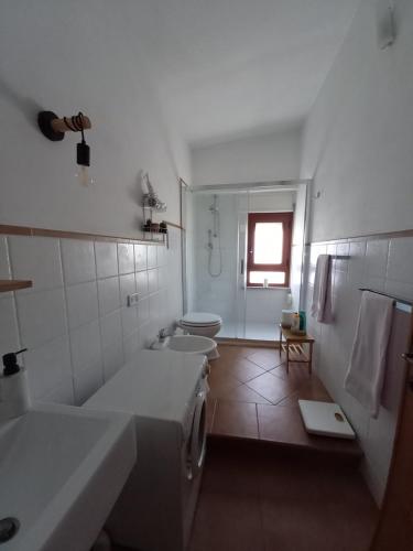 een badkamer met 2 wastafels, een bad en een toilet bij Casa Sui Tetti in Baunei