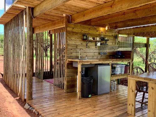 an outdoor kitchen with wooden walls and a wooden deck at Mudhouse Zululand in Hluhluwe