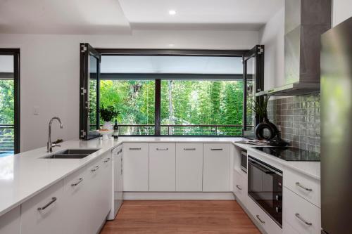 a kitchen with white cabinets and a large window at Light Filled Modern Specious Home, Pet friendly in a beautiful area of Byron Bay, short stroll to town in Byron Bay