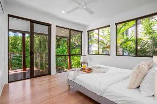 a bedroom with a bed and large windows at Light Filled Modern Specious Home, Pet friendly in a beautiful area of Byron Bay, short stroll to town in Byron Bay