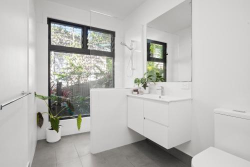 a white bathroom with a sink and a mirror at Light Filled Modern Specious Home, Pet friendly in a beautiful area of Byron Bay, short stroll to town in Byron Bay