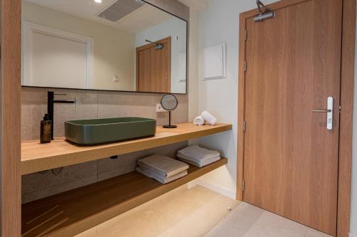 a bathroom with a green sink and a mirror at Hotel Santanyi Port in Cala Figuera