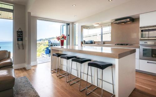 a kitchen with a large counter with stools at Oneroa Bay - Be My Guest Waiheke in Blackpool