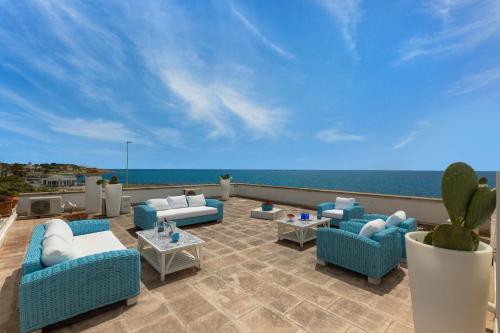 un patio con sillas y mesas azules y el océano en Villa Zio Tore by BarbarHouse, en Torre Suda