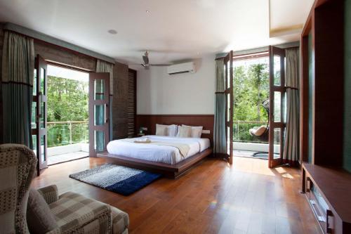 a bedroom with a bed and large windows at StayVista at The Yercaud Bungalow with Pvt Pool in Yercaud