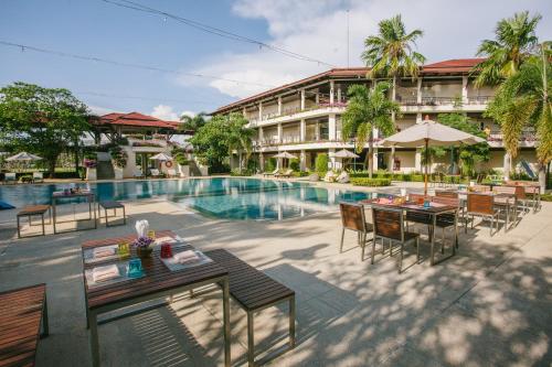 una imagen de un complejo con piscina, mesas y sillas en Maneechan Resort - SHA Extra Plus en Chanthaburi