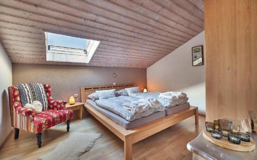 a bedroom with a large bed and a red chair at Ferienwohnung Fritz in Bodenmais