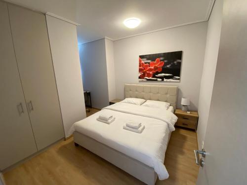 a bedroom with a white bed and a painting on the wall at Spetson Modern 56sqm apt in Piraeus in Piraeus