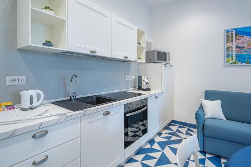 a kitchen with white cabinets and a blue chair at Blumare Home in Vico Equense