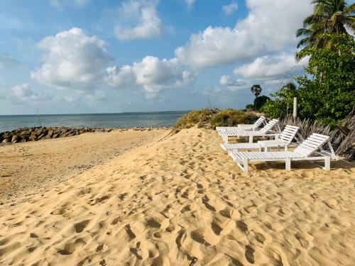 a row of white chairs sitting on a sandy beach at Windy Waves Kite Beach & Nature Resort in Kalpitiya
