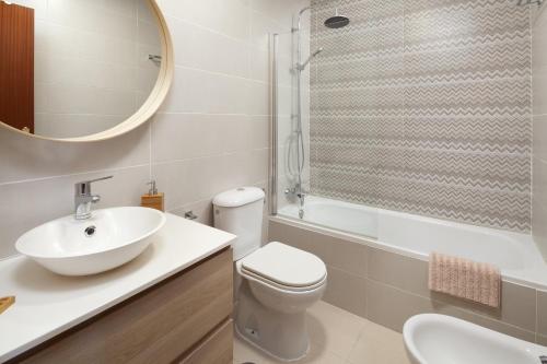 een badkamer met een wastafel, een toilet en een spiegel bij Monte Meru in Chilches