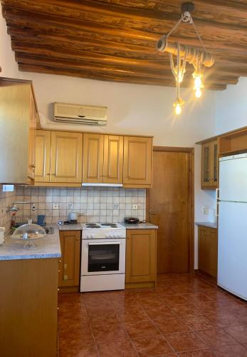 eine Küche mit Holzschränken und einem weißen Herd mit Backofen in der Unterkunft Stefanoula's house in Kimolos