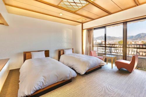 a bedroom with two beds and a balcony at Japanese Onsen Ryokan Kohakuen in Fuefuki