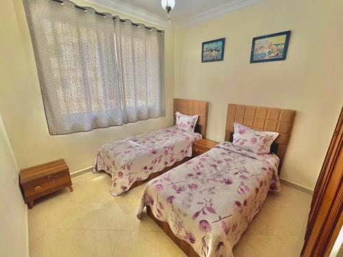 1 dormitorio con 2 camas y ventana en Joli appartement a la corniche de Tanger, en Tánger