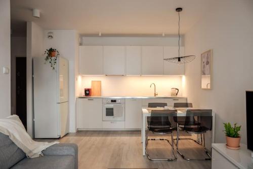 a kitchen with white cabinets and a table and chairs at Platinum Jaglana Apartment - Wyspa Spichrzów in Gdańsk