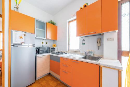 eine Küche mit orangefarbenen Schränken und einem weißen Kühlschrank in der Unterkunft Casa Chanty by Rentbeat in Ostuni